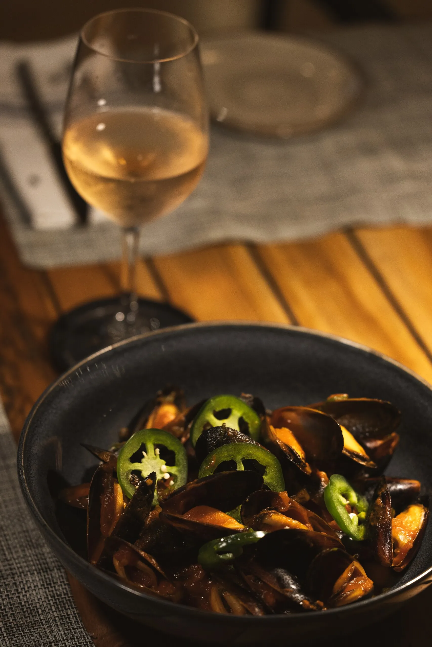 Mussels with sliced jalapenos and a glass of wine at Manzu