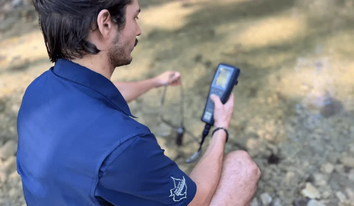 Nantipa team member using a handheld water quality monitor at a local stream in Santa Teresa, Costa Rica