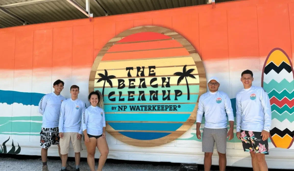 Nantipa team in NP Waterkeeper beach cleanup shirts posing in front of The Beach Cleanup mural in Santa Teresa